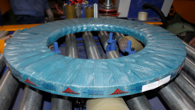 Automated stretch wrapping machine applying film to a steel coil for secure packaging