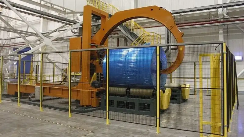 A wide shot of a complete heavy-duty coil packaging line with multiple stations