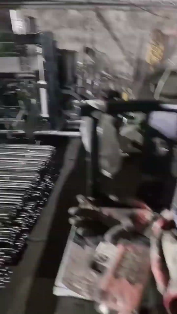 A hand and forearm entering the frame beside a bundle of steel bars under a tying machine