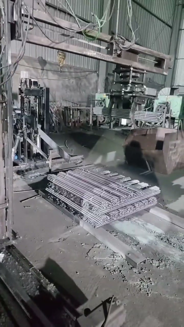 A bundle of steel bars resting on the platform beneath the tying machine frame at the end of the clip
