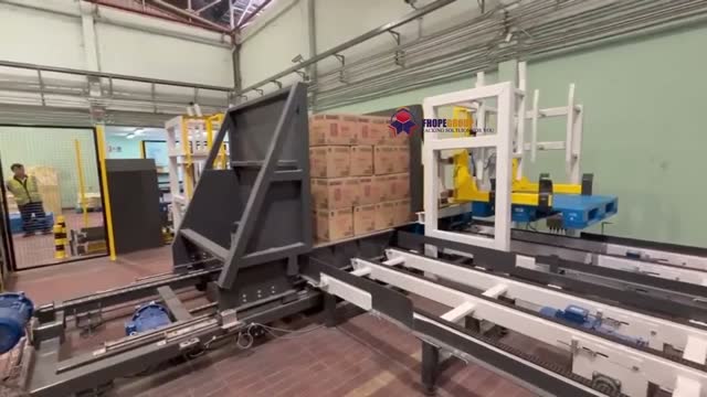 A palletized stack being pushed along a track into a transfer cell on a pushing-type pallet line