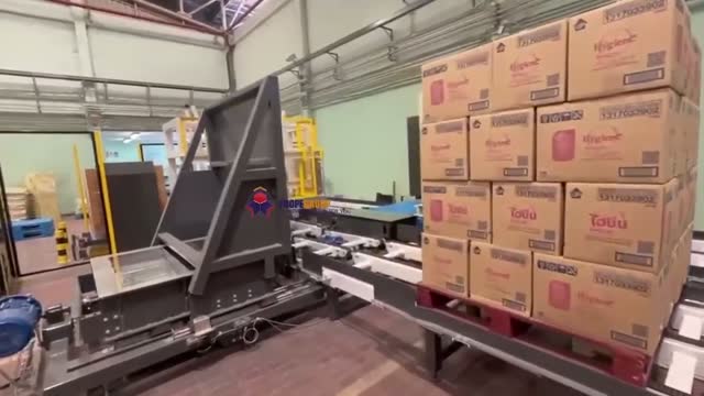 A palletized stack on a yellow turntable just before a ninety degree turn