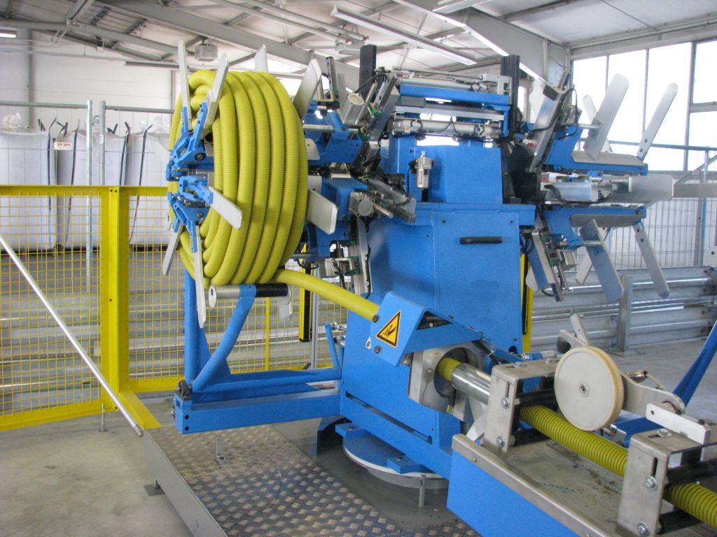 A pipe and hose coiling machine holding a finished coil of corrugated hose
